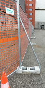 Recinzione provvisoria con pannelli metallici, basi zavorrate e rete arancione