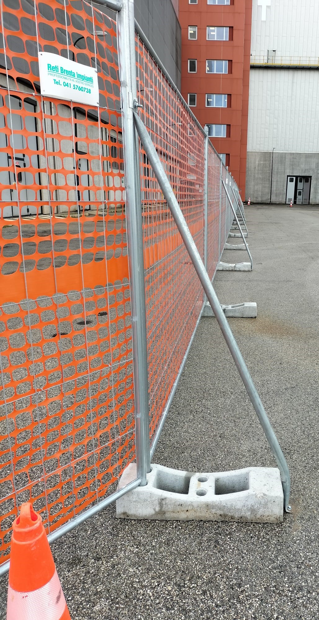 Recinzione provvisoria con pannelli metallici, basi zavorrate e rete arancione