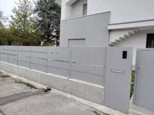 Testo alternativo dell’immagine Recinzione grigia a doghe orizzontali con cancello pedonale coordinato